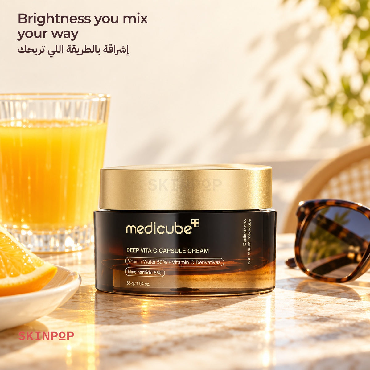 Medicube Deep Vita C Capsule Cream beside a glass of orange juice and sunglasses