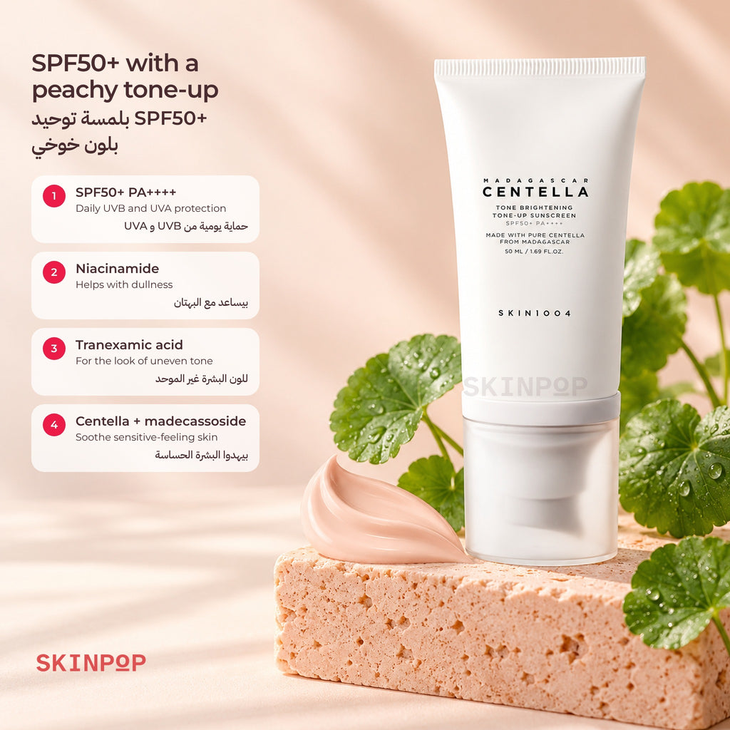 SKIN1004 Tone-Up Sunscreen tube on a peach stone block with fresh centella leaves